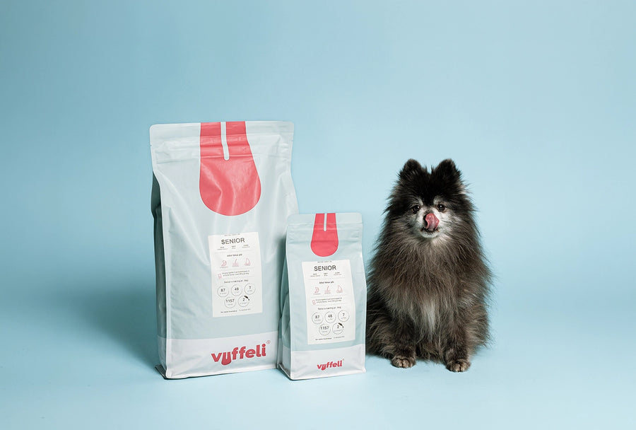 Felix ældre pomeranian slikker sig om munden ved siden af Vuffelis seniorfoder i en stor og en lille pose